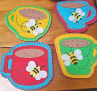 Colorful felt coasters with bee designs on a wooden surface