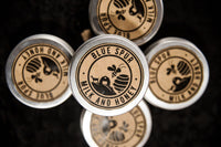 A group of four cylindrical metal tins with a design that includes a honeycomb pattern and the words 'Blue Spur Milk and Honey'.