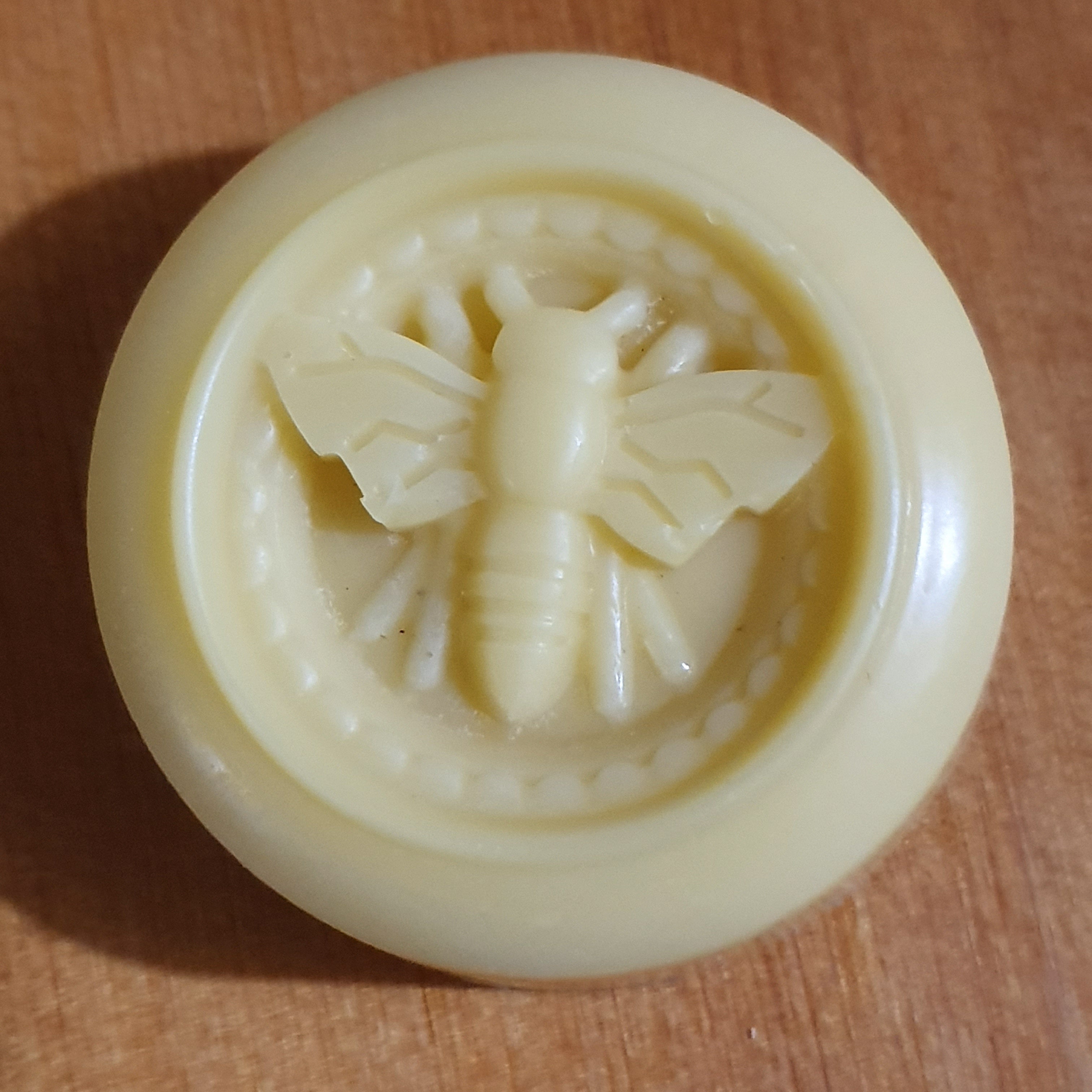 Round yellow solid hand lotion with a bee design on a wooden surface