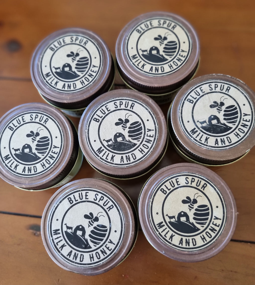 Multiple jars of Blue Spur Milk and Honey  products on a wooden surface