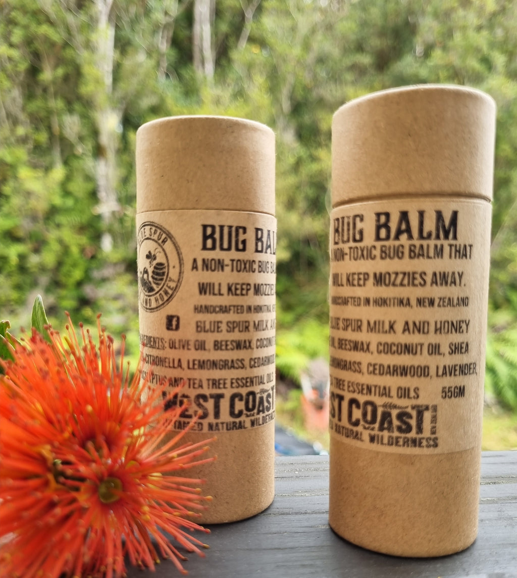Two eco-friendly tubes of natural West Coast Bug Balm on a wooden surface with a blurred natural background