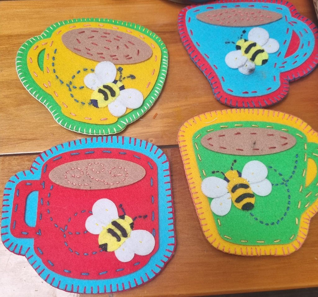 Colorful felt coasters with bee designs on a wooden surface