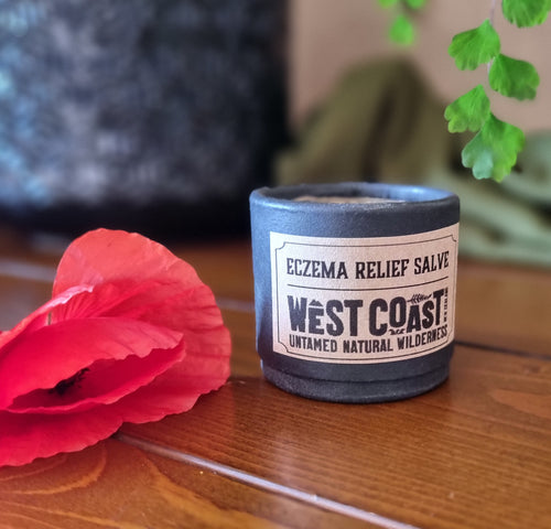 West Coast Eczema Relief Salve container with a red flower on a wooden surface