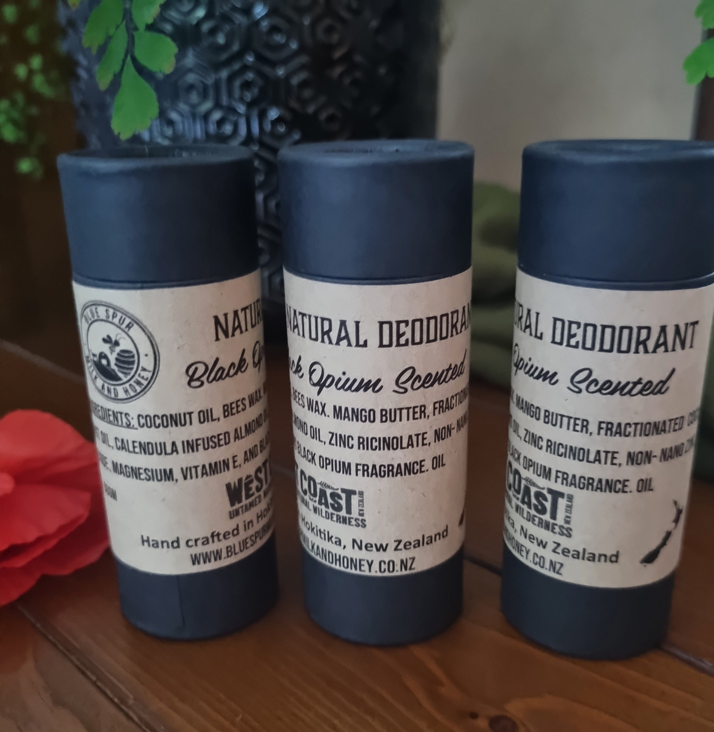 Three black opium natural deodorants in black paperboard tubes with natural paper label and a poppy flower