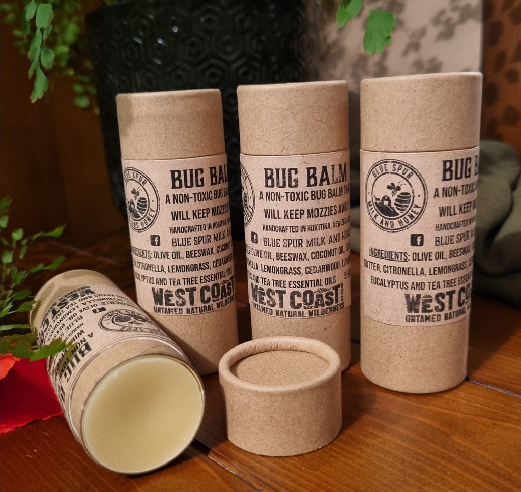 West Coast natural Bug Balm containers on a wooden surface with a blurred natural background