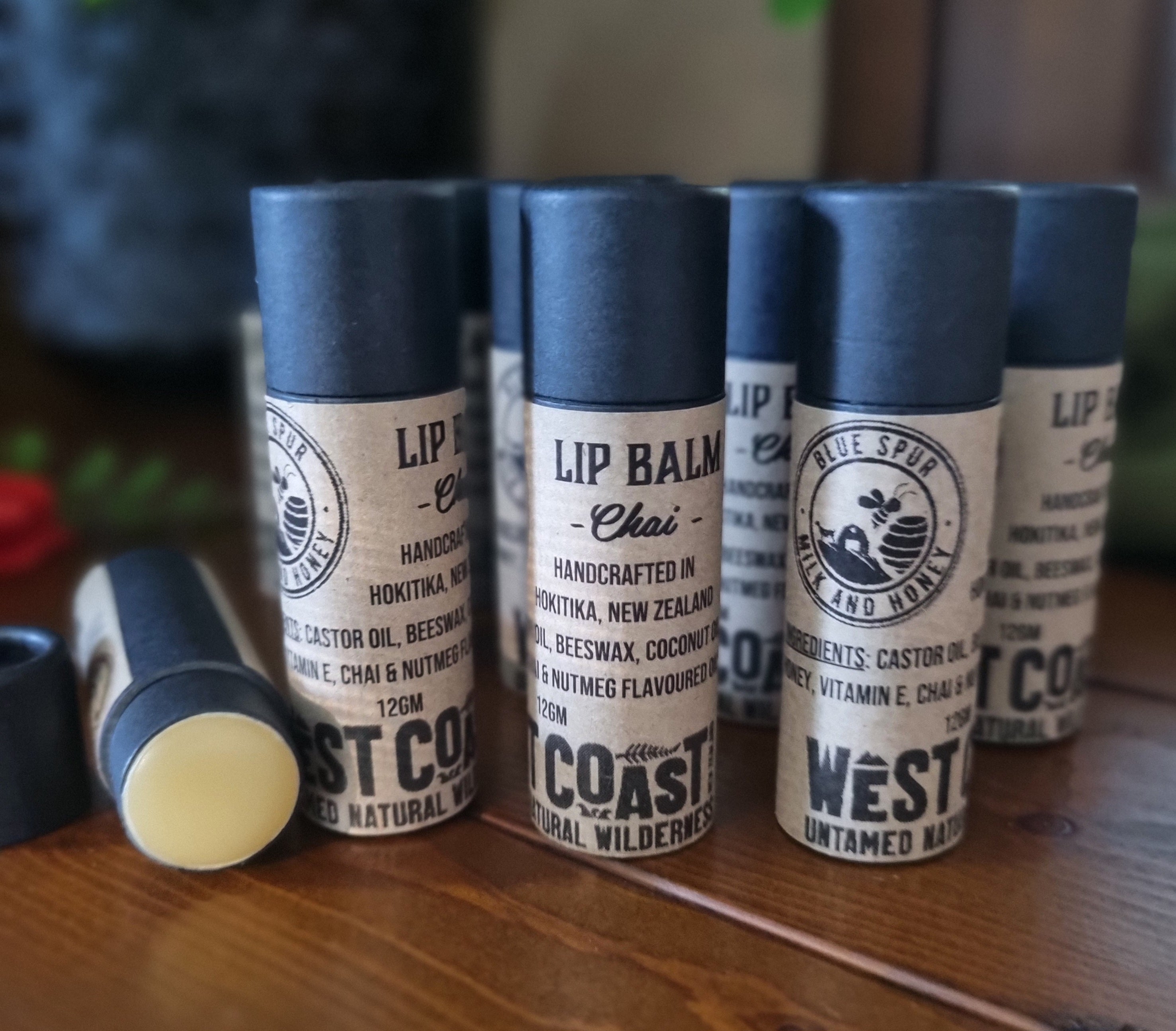 Set of lip balm containers with visible branding on a wooden surface.