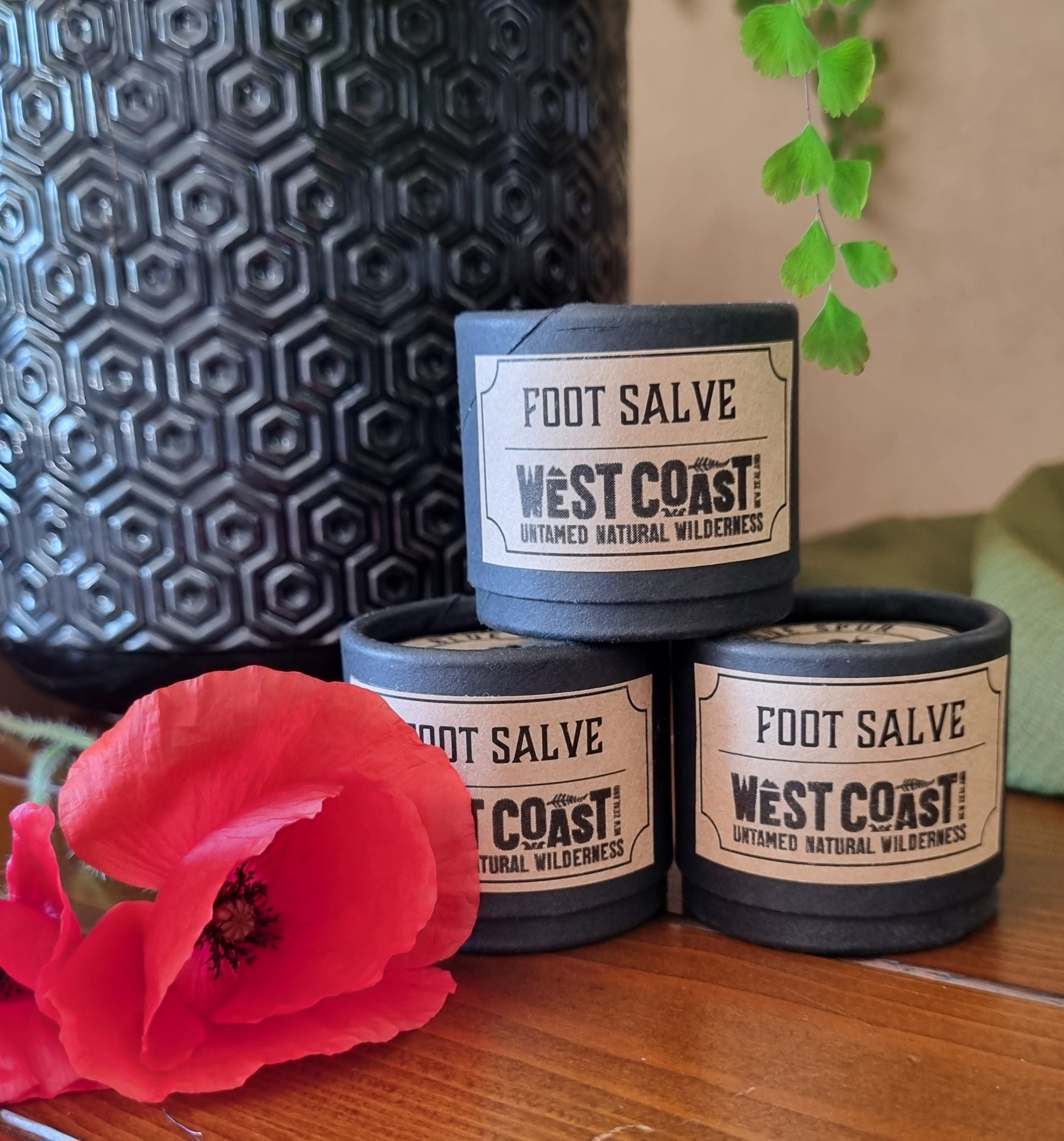 Three 20gm black paperboard jars of foot salve with a red poppy