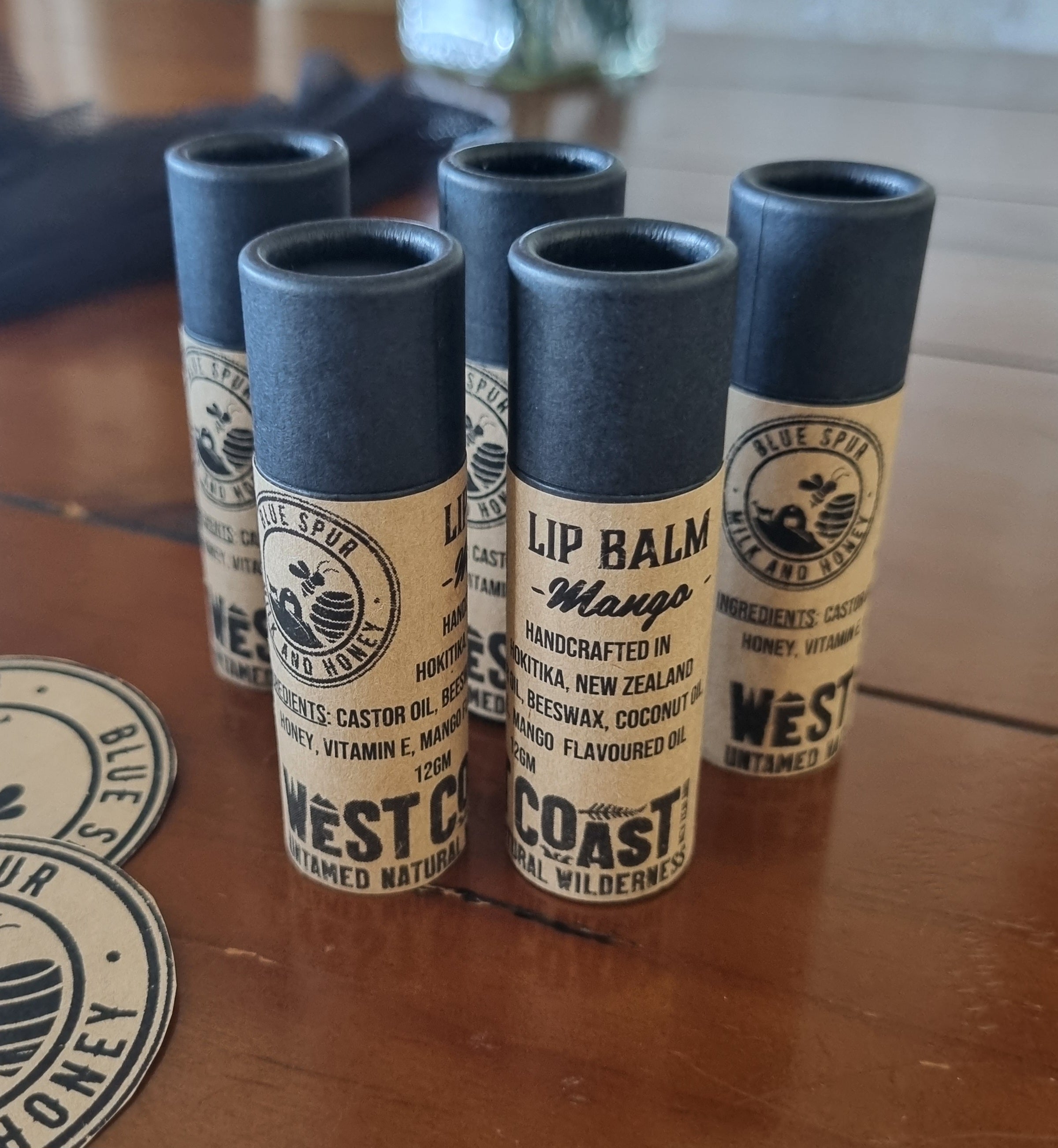 West Coast lip balm tubes on a wooden surface