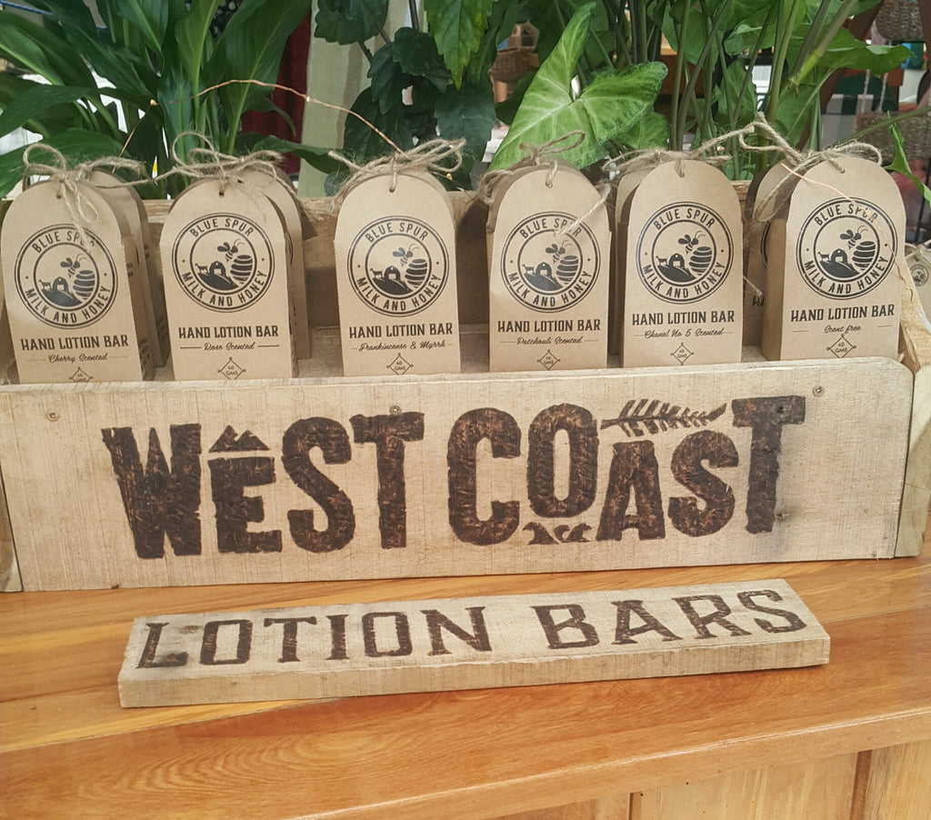 wooden stand with branded boxes of lotion bars with plants in the background