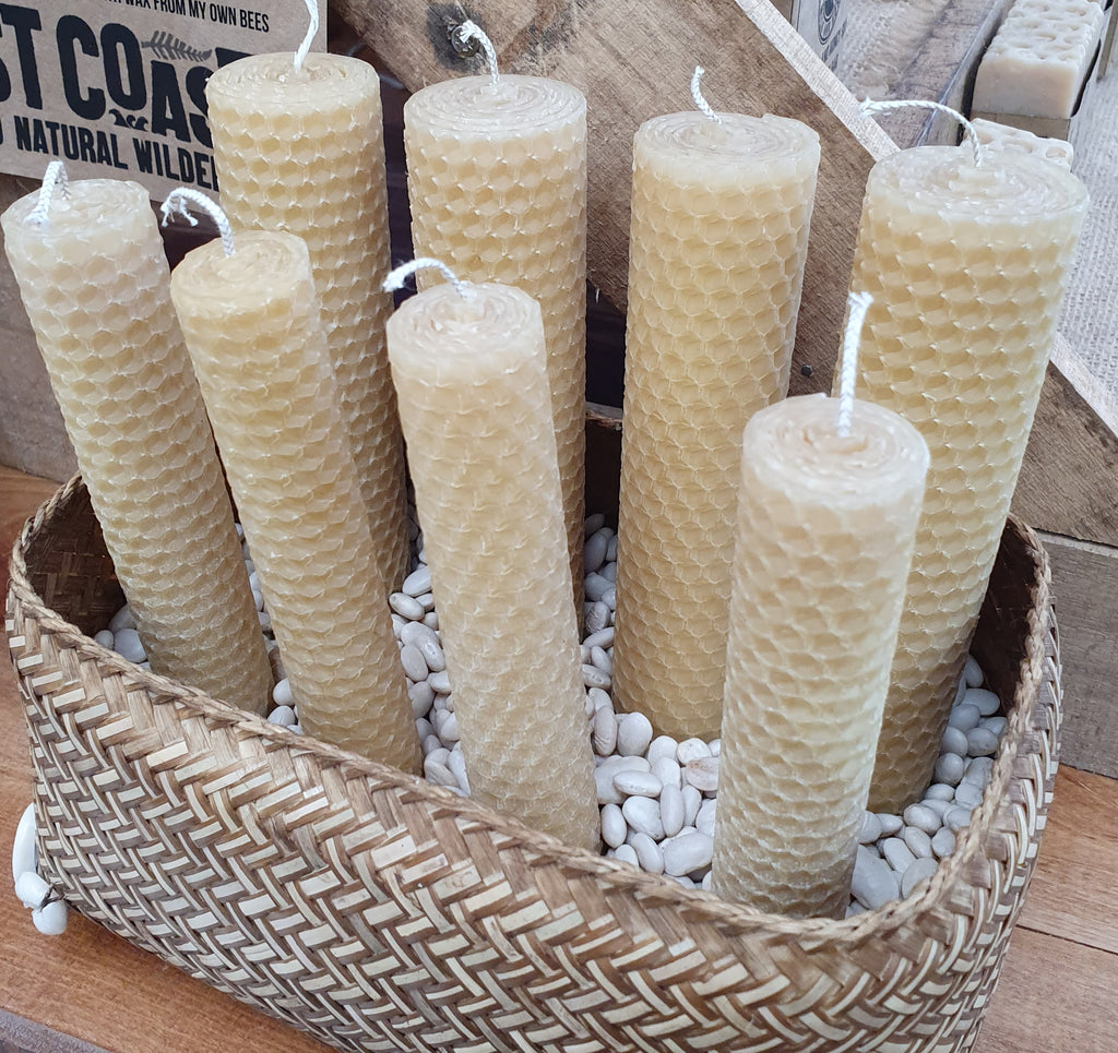 A set of eight beeswax candles with natural hemp wicks, displayed in a woven basket.